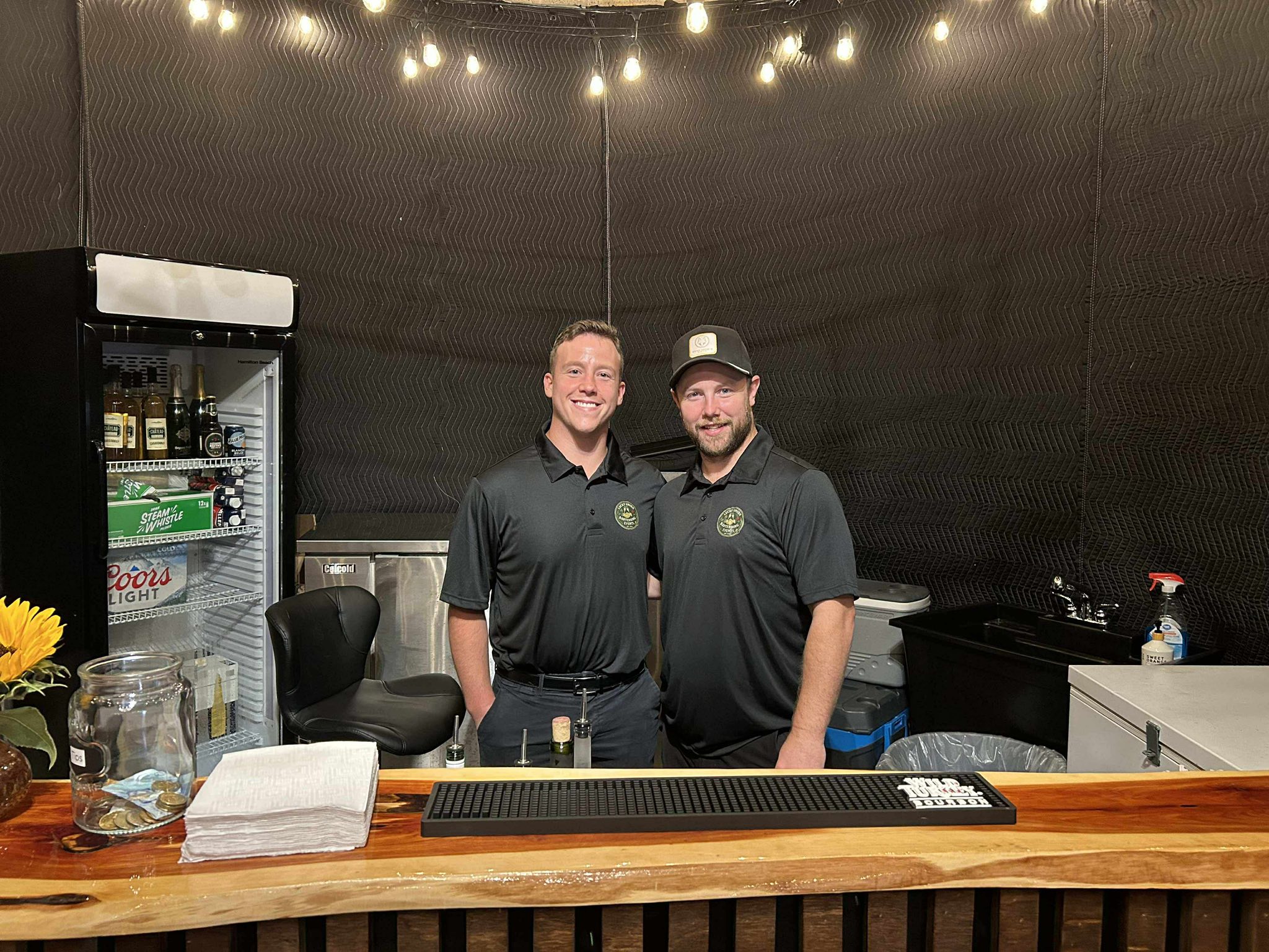 Lucky Union bartenders behind a wood-top bar with string lights overhead